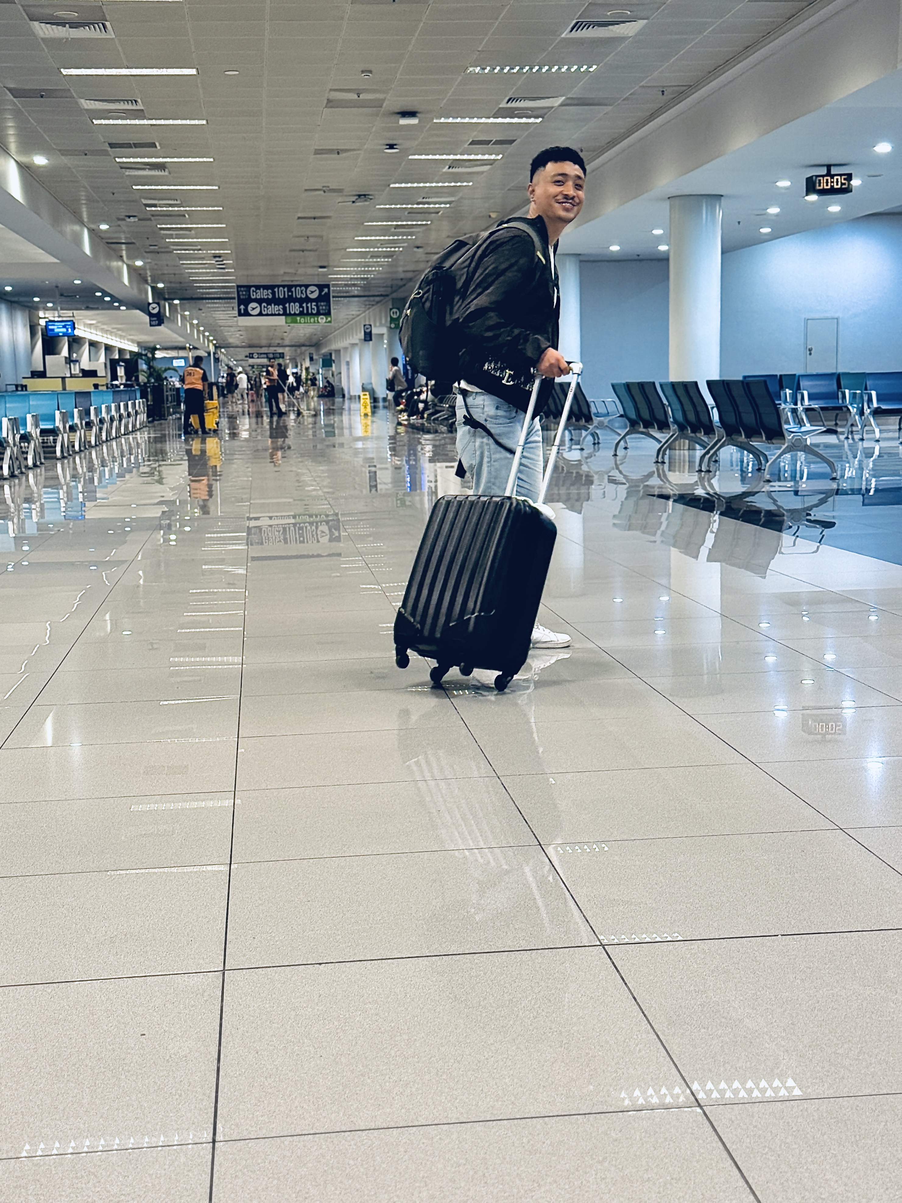 Dylan at the airport smiling with luggage — on the move as a digital nomad