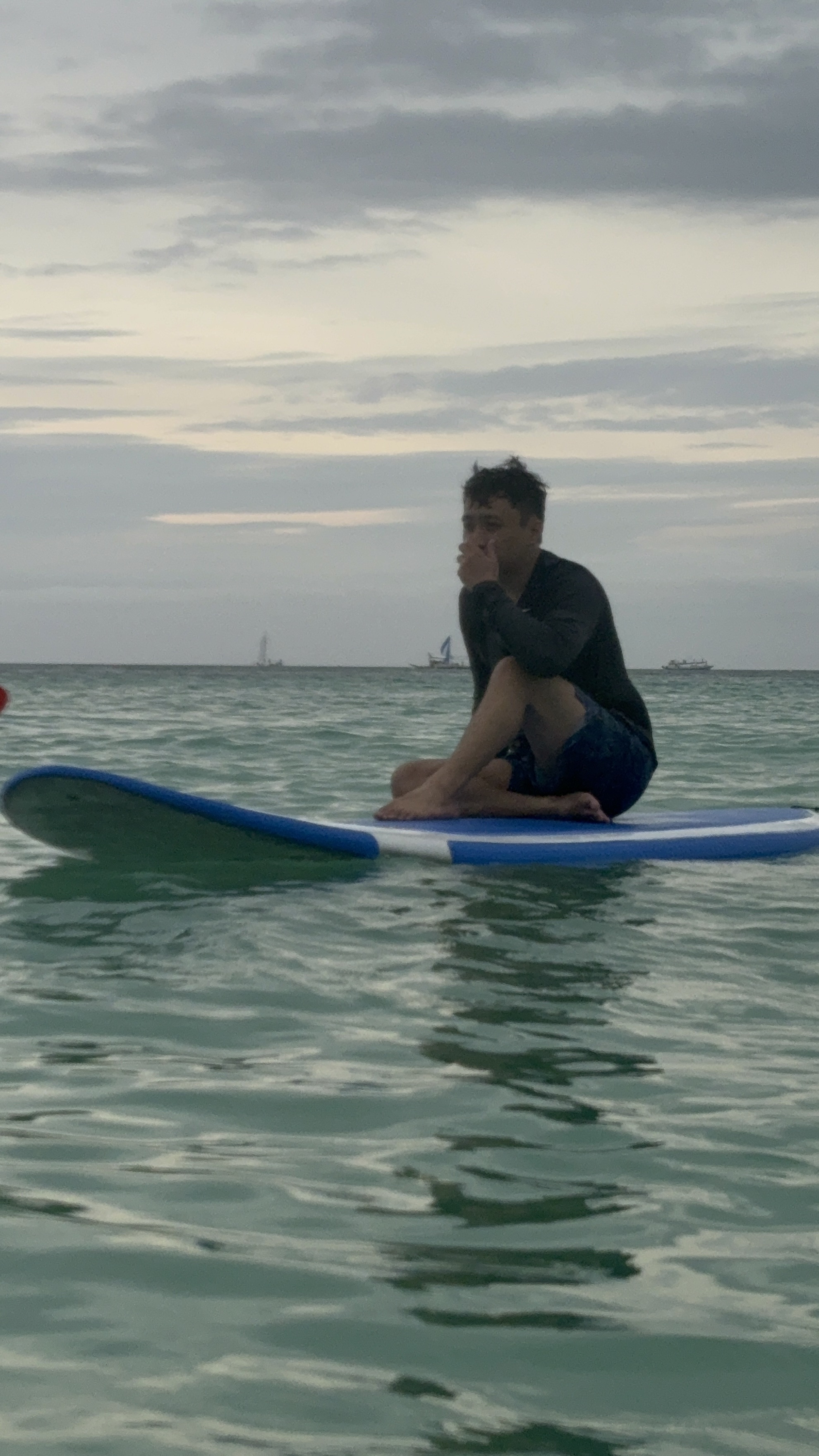 Dylan sitting quietly on a surfboard in the open ocean